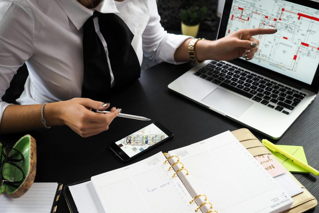A business professional working on real estate project plans using multiple devices in an office setting.