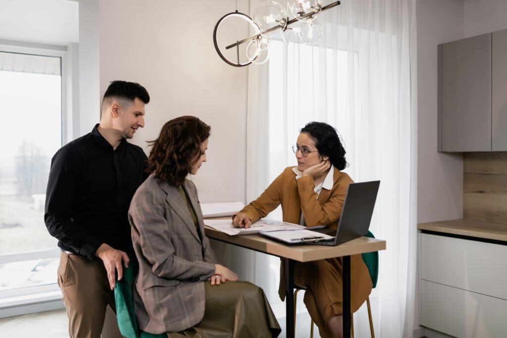 A couple consults a real estate agent in a modern office setting.