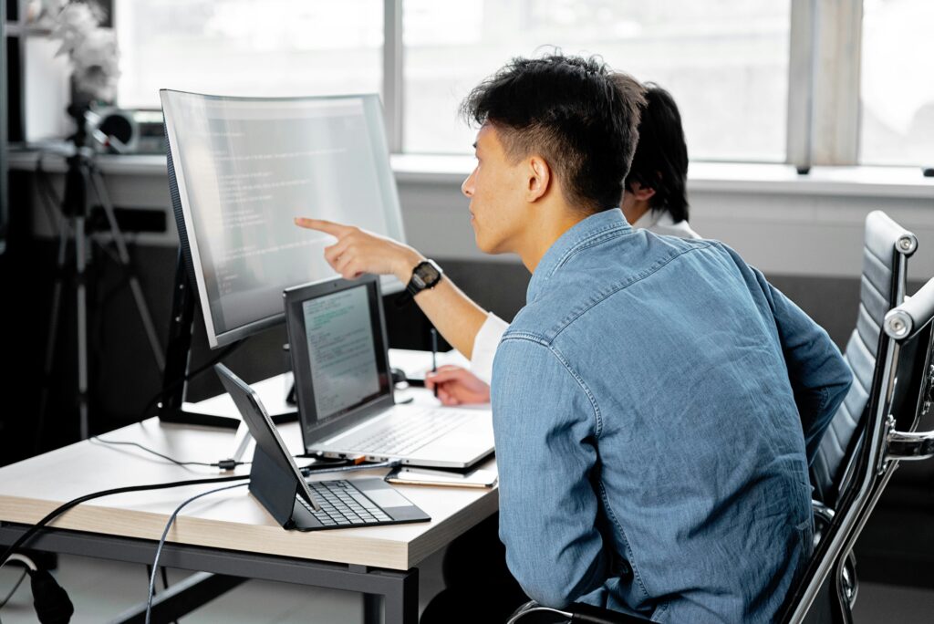 Professionals collaborating at a tech-centric workspace with laptops and monitors.